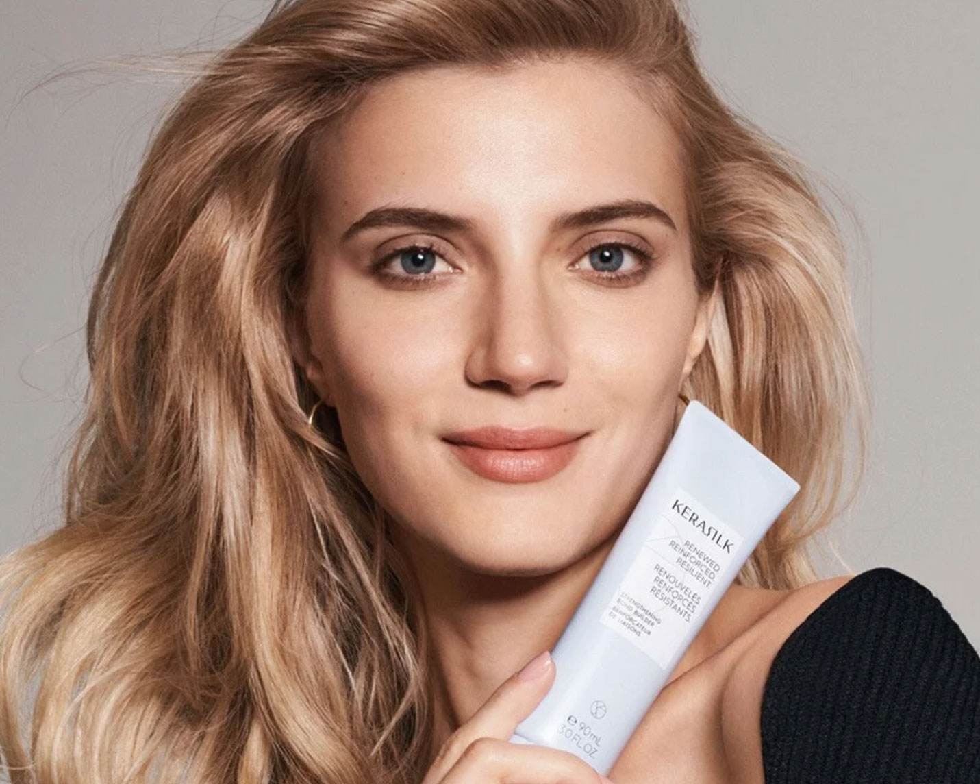 Produktaufnahme einer lächelnden Frau, die das Produkt in der Hand hält und freundlich in die Kamera schaut. 